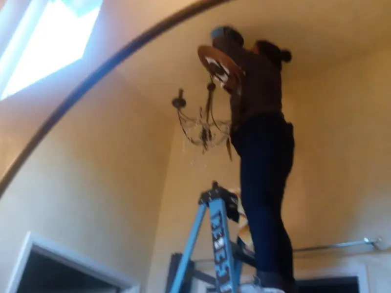 Electrician installing a chandelier in a Elroy residence